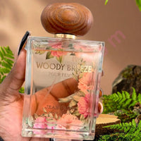 Thumbnail for Perfume bottle labeled 'Woody Breeze' held by a hand with a natural background