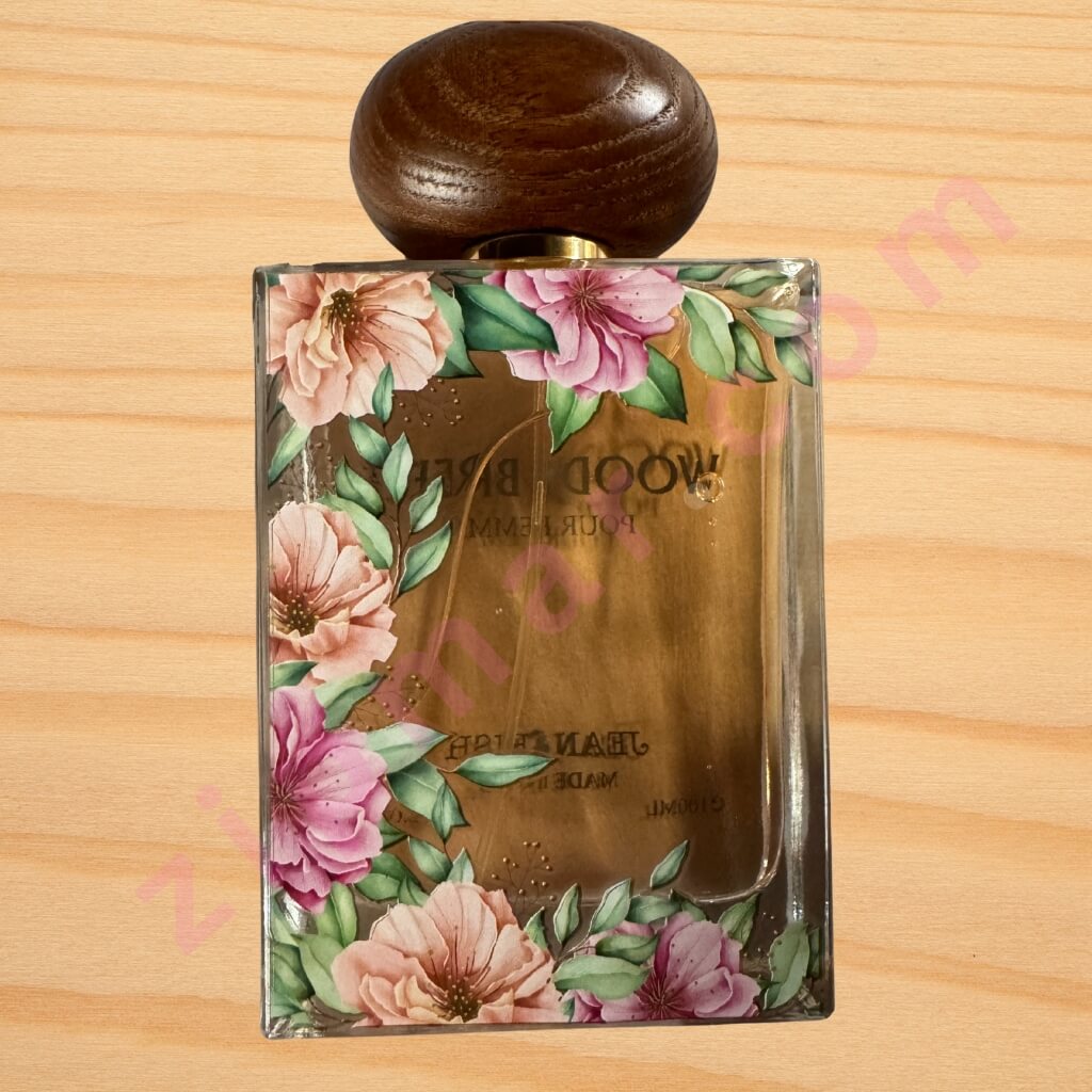 Perfume bottle with floral design on a wooden surface