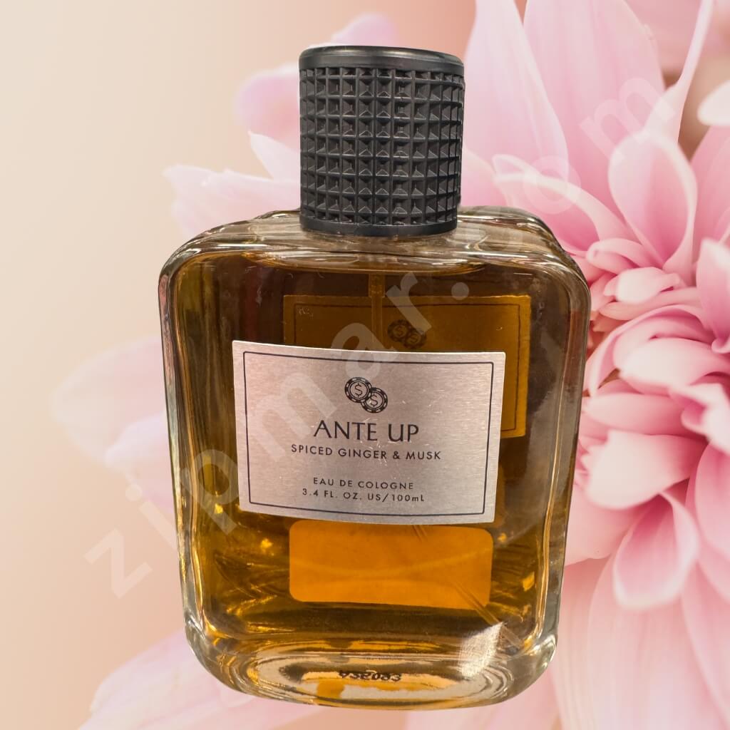 Perfume bottle labeled 'Ante Up' with pink flowers in the background