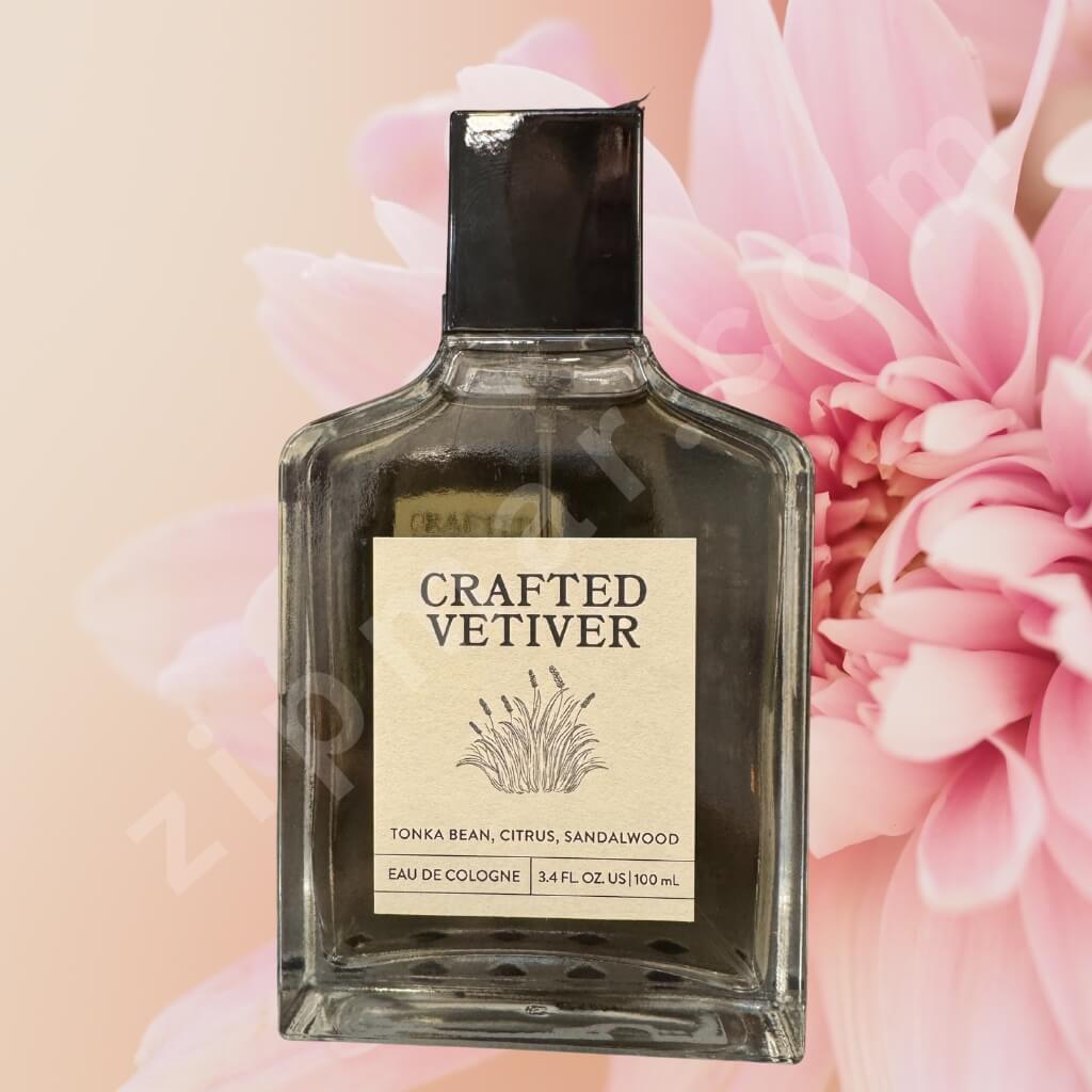 Perfume bottle labeled 'Crafted Vetiver' with pink flowers in the background