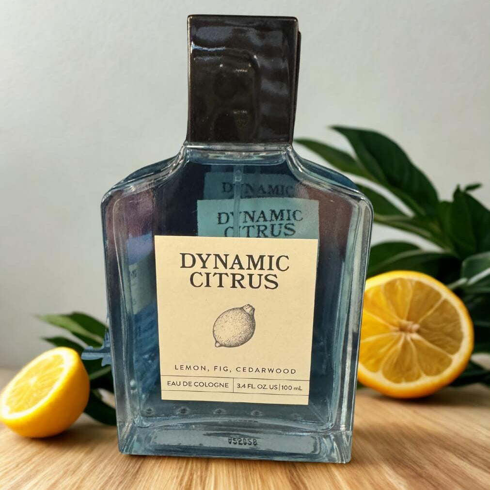 Bottle of Dynamic Citrus cologne with lemons and greenery in the background