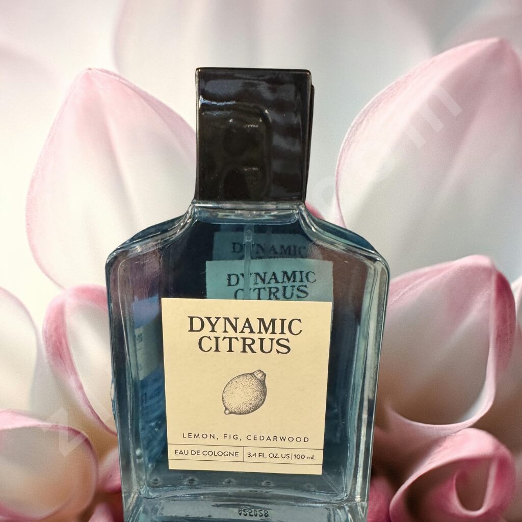 Bottle of Dynamic Citrus cologne with a pink floral background