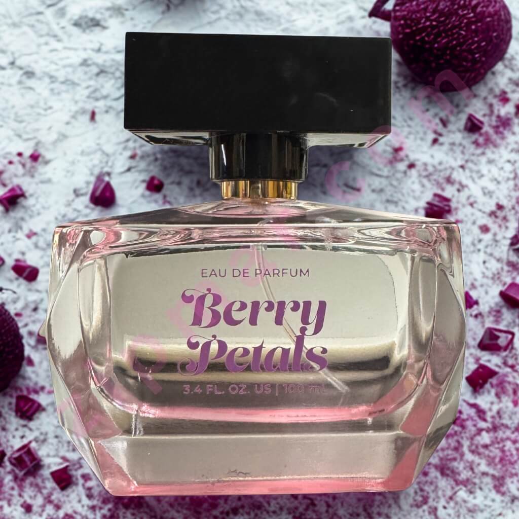 Perfume bottle labeled 'Berry Petals' on a textured surface with purple flowers.