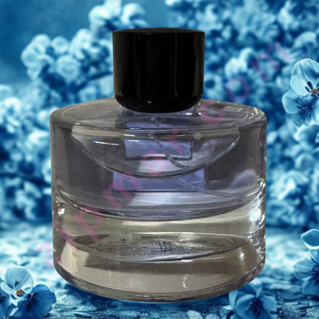 Clear glass perfume bottle with black cap on a blue floral background