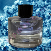 Thumbnail for Clear glass perfume bottle with black cap on a blue floral background