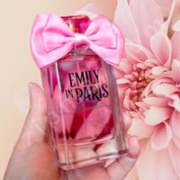 Thumbnail for Perfume bottle with pink bow and 'Emily in Paris' branding held against a pink floral background