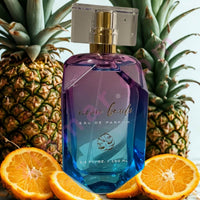 Thumbnail for Blue perfume bottle with gold cap on a white surface, surrounded by pineapples and oranges.