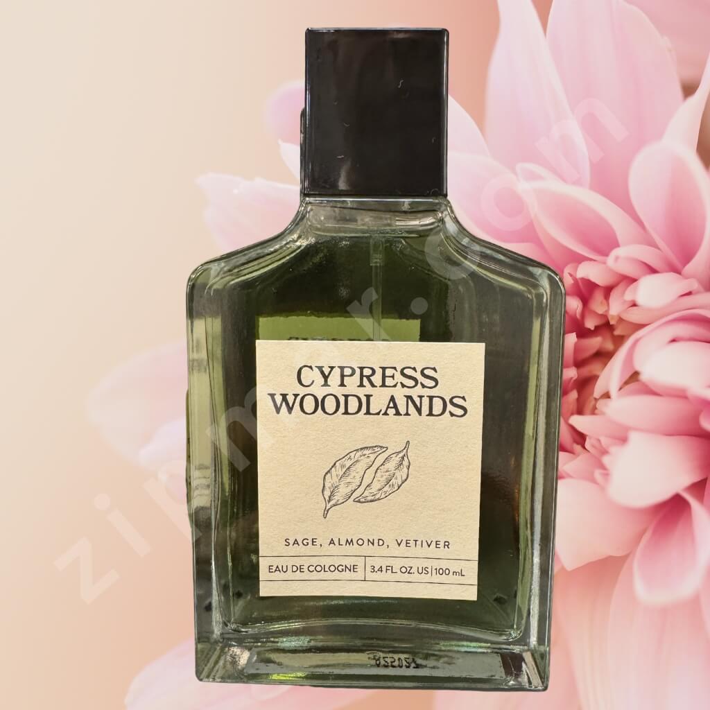 Bottle of Cypress Woodlands cologne with a pink flower in the background