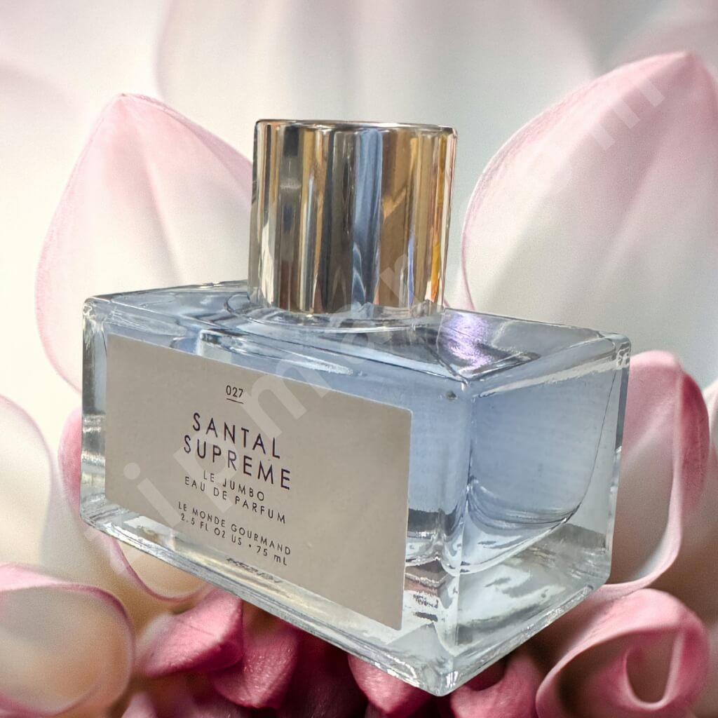 Santal Supreme perfume bottle with pink flowers in the background