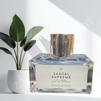 Thumbnail for Santal Supreme perfume bottle on a white surface with a plant in the background