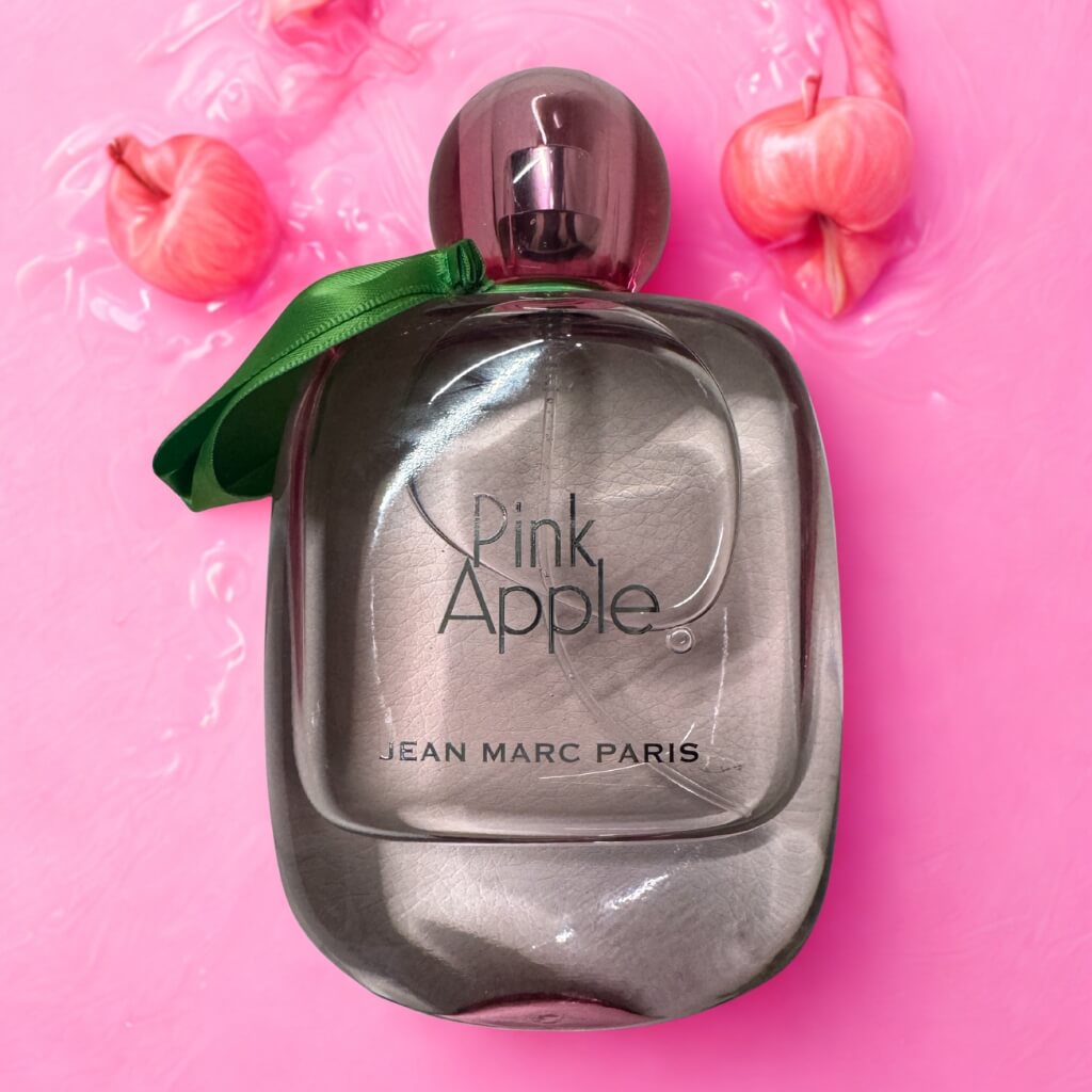 Perfume bottle labeled 'Pink Apple' by Jean Marc Paris on a pink background with decorative apples.