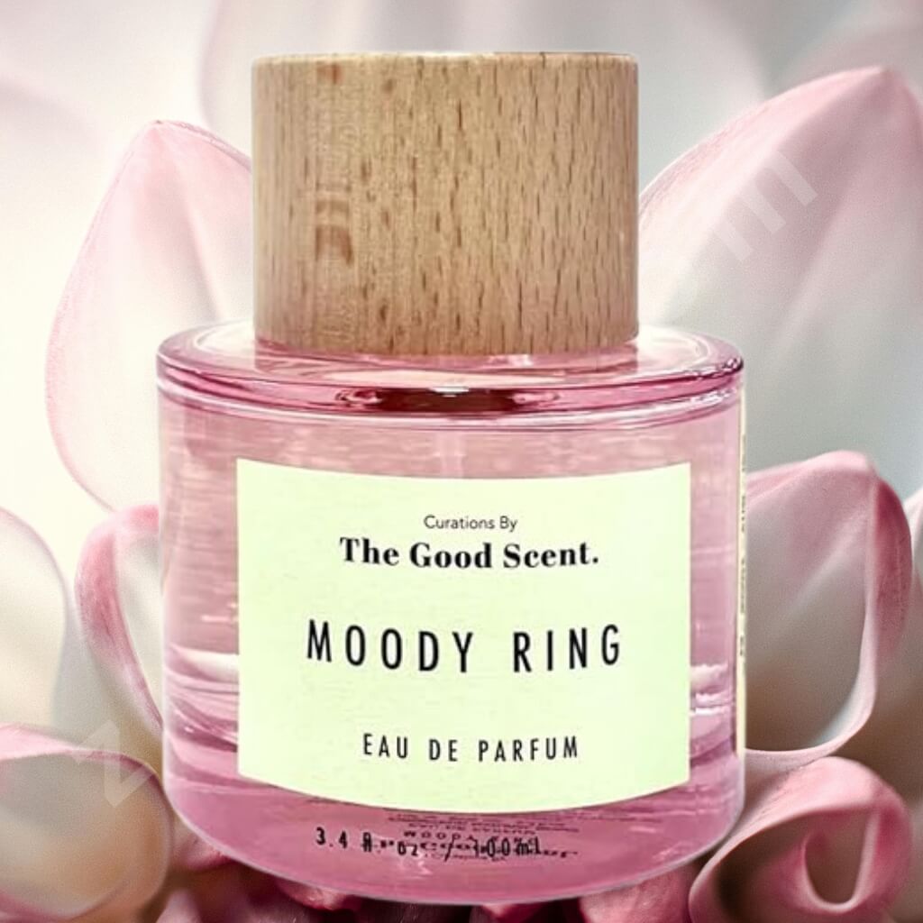 Pink eau de parfum bottle with wooden cap labeled 'Moody Ring' by 'The Good Scent' on pink floral background