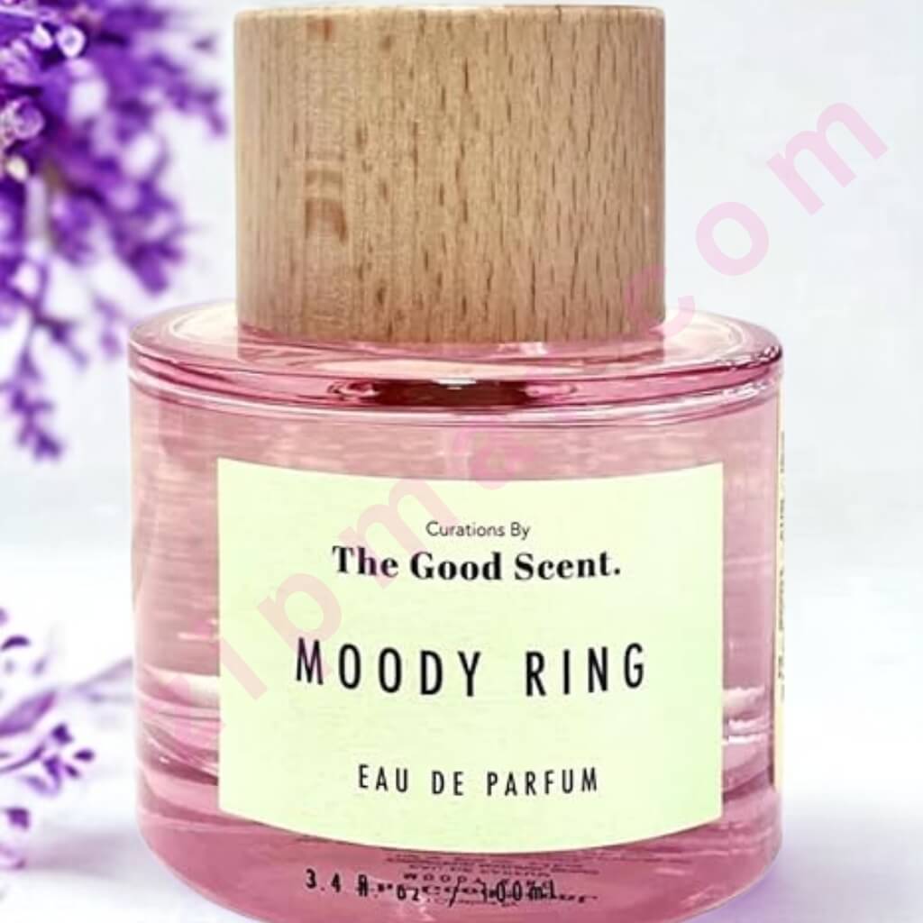 Pink perfume bottle labeled 'Moody Ring' by 'The Good Scent' with a wooden cap on a light pink background.