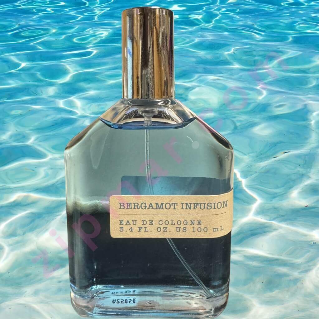 Perfume bottle labeled 'Bergamot Infusion' on a blue water background