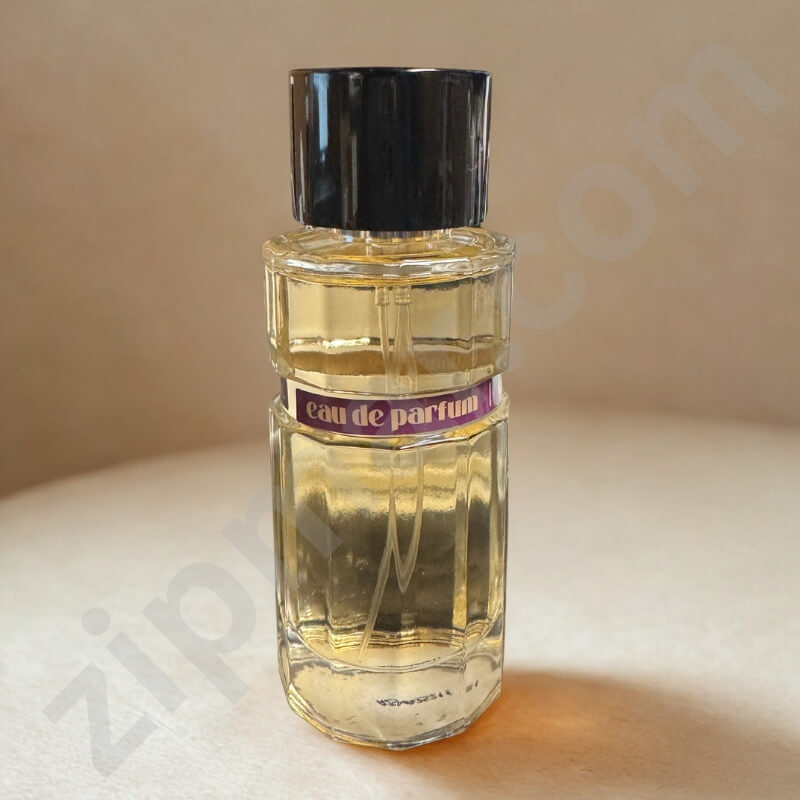 Perfume bottle labeled 'eau de parfum' on a beige surface with a blurred background.