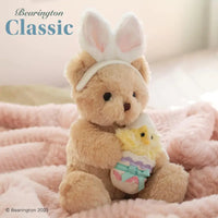 Thumbnail for Bearington Classic Beary Eggstra teddy bear with bunny ears sitting on blanket