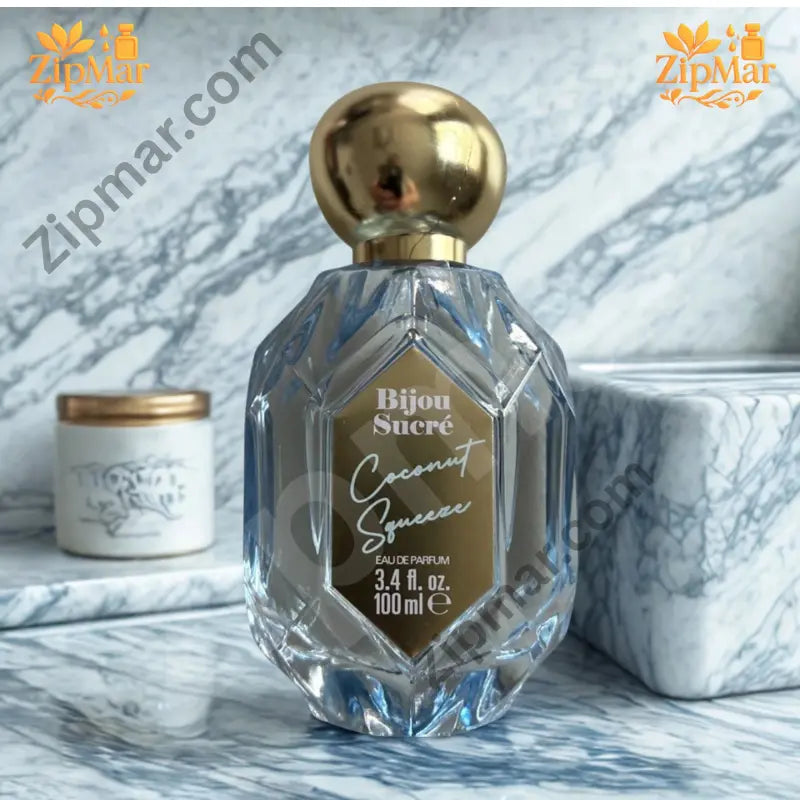 Bijou Sucré Coconut Squeeze perfume bottle with gold cap on a blue marble surface