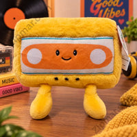 Thumbnail for Yellow cassette tape plush with smiley face styled with vinyl records and books”