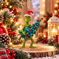 Thumbnail for Enesco Jim Shore Grinch stealing Christmas tree ornament lifestyle Grinch in Santa hat leaning forward holding decorated tree with colorful ornament balls and gold star topper