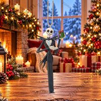 Thumbnail for Enesco Jim Shore Jack Skellington ornament from Nightmare Before Christmas — tall skeletal Pumpkin King in black suit holding green Christmas gift, cozy fireplace living room scene