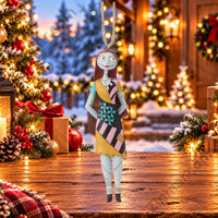 Thumbnail for Enesco Jim Shore Sally ornament from Nightmare Before Christmas — rag doll in colorful patchwork folk art dress with teal, pink, black and gold panels, snowy Christmas cabin scene