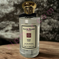 Thumbnail for Perfume bottle labeled 'Olivia Blake London' on a wooden surface with a blurred background
