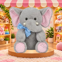Thumbnail for Gray elephant plush toy sitting on a wooden stand with pink polka dot ears and feet, white tusks and a blue polka dot bow