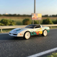 Thumbnail for Hot Wheels MTV 84 Corvette diecast car photographed outdoors on roadside
