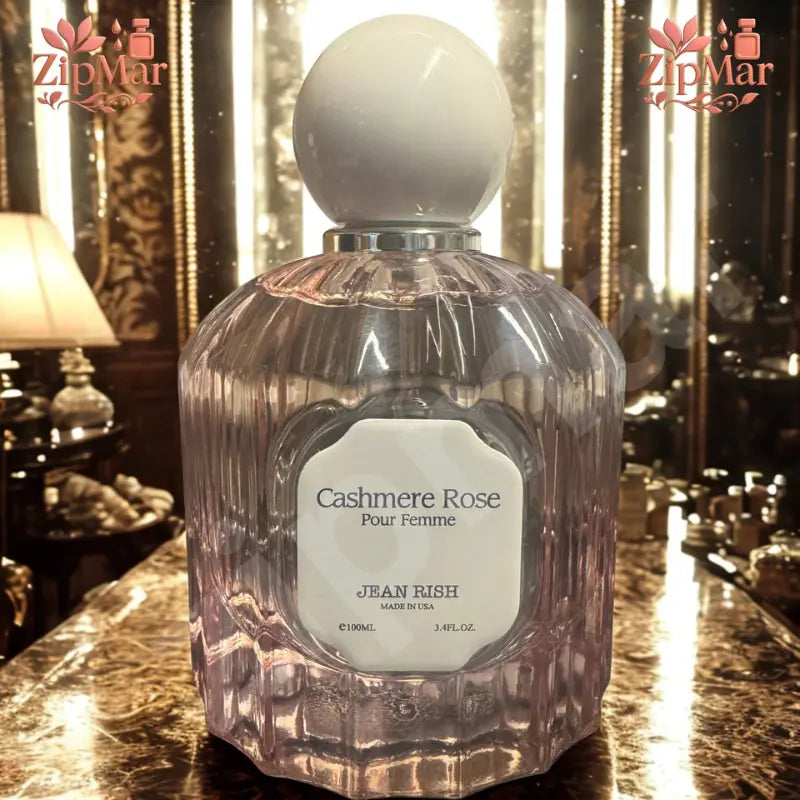 Jean Rish Cashmere Rose Pour Femme Eau de Parfum 3.4 fl oz fluted pink glass bottle with cream cap on a marble counter