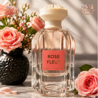 Thumbnail for Jean Rish Rose Fleur 3.4 fl oz 100 mL fluted glass bottle with coral label beside pink roses