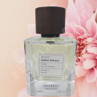 Thumbnail for Perfume bottle labeled 'Amber Intense' with a pink flower in the background