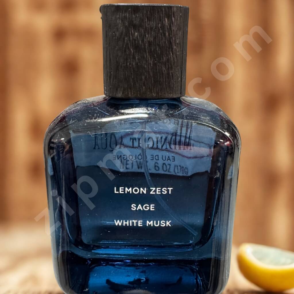 Perfume bottle labeled 'Lemon Zest, Sage, White Musk' with a wooden cap on a blurred background.