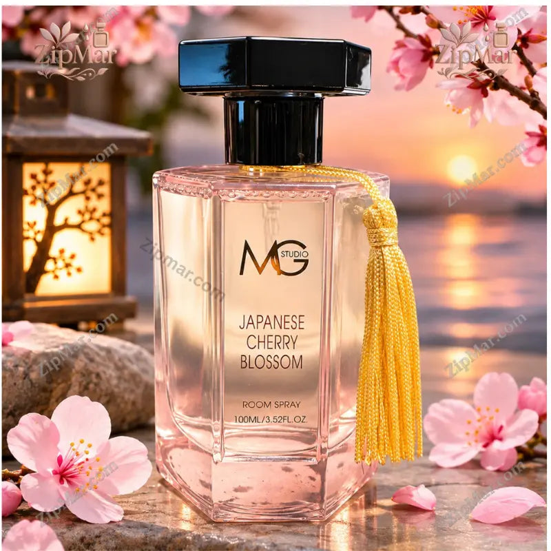 MG Studio Japanese Cherry Blossom Room Spray 100 mL pink bottle with gold tassel beside cherry blossoms at sunset