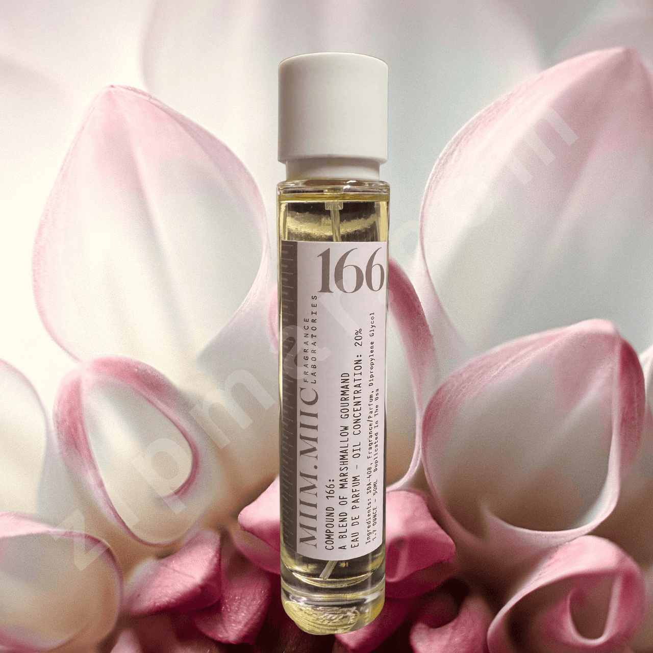 Small bottle of perfume with a label on pink flower petals