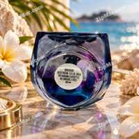 Thumbnail for Neon Beach Eau de Parfum 100ml inverted bottle showing circular bottom label — Neon Beach EDP 3.4 fl oz 100ml Tru Fragrance and Beauty LLC Willowbrook IL 60527 tropical beach lifestyle setting with white plumeria frangipani flowers white coral sea fan and sparkling turquoise ocean background