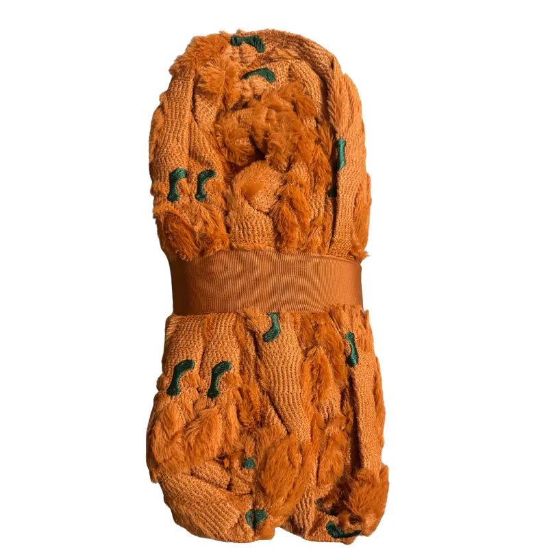 Side profile view of folded pumpkin embroidered faux fur throw blanket