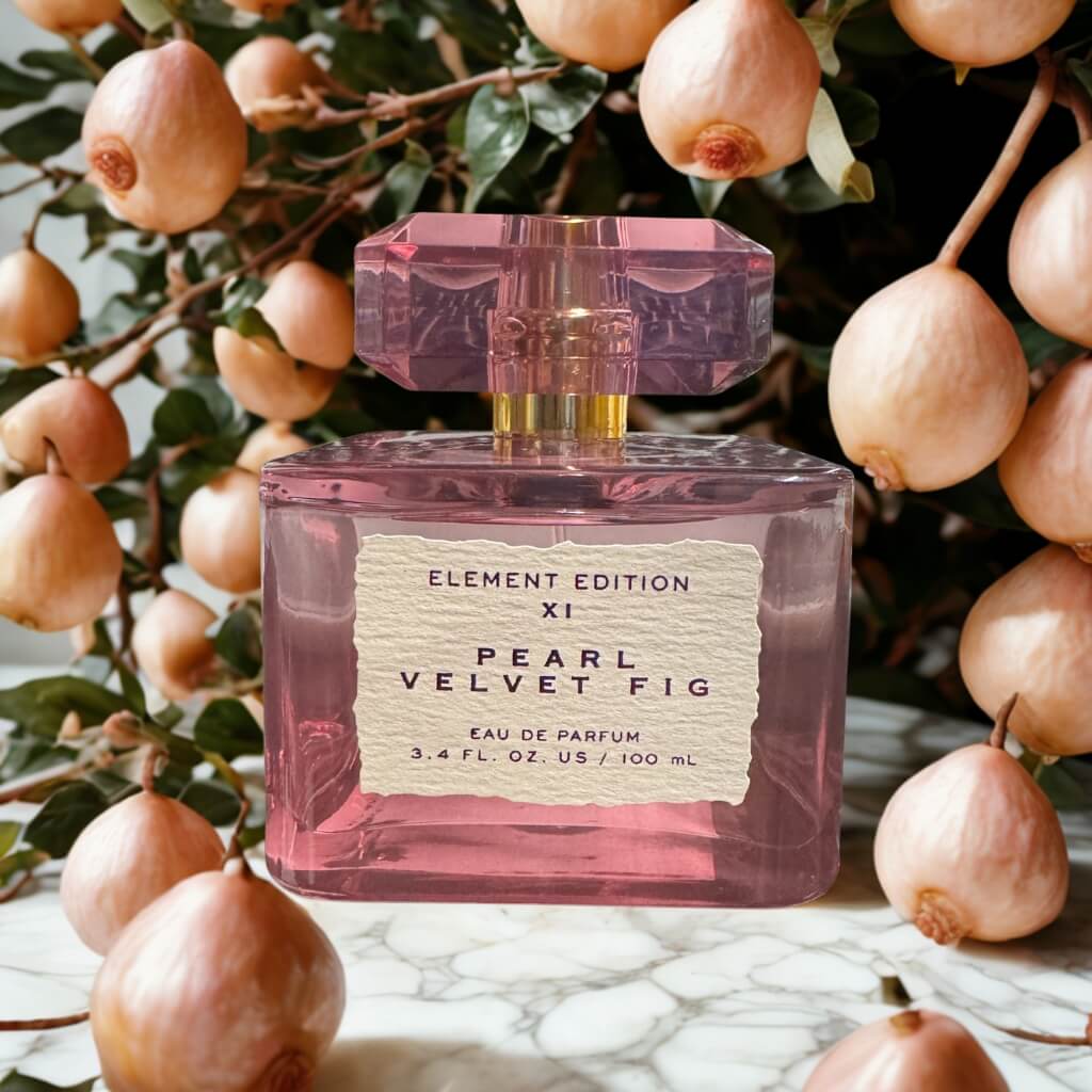 Perfume bottle labeled 'Pearl Velvet Fig' with fruit in the background