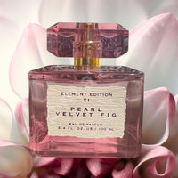 Thumbnail for Pink perfume bottle labeled 'Pearl Velvet Fig' on a pink floral background