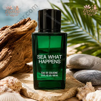 Thumbnail for Sea What Happens Eau de Cologne 3.4 oz emerald green square bottle in coastal setting with seashells, driftwood, palm fronds, and ocean backdrop
