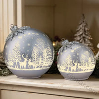 Thumbnail for Set of 2 silver gray glass ornament decor pieces with white reindeer and winter forest scene glowing on a white shelf