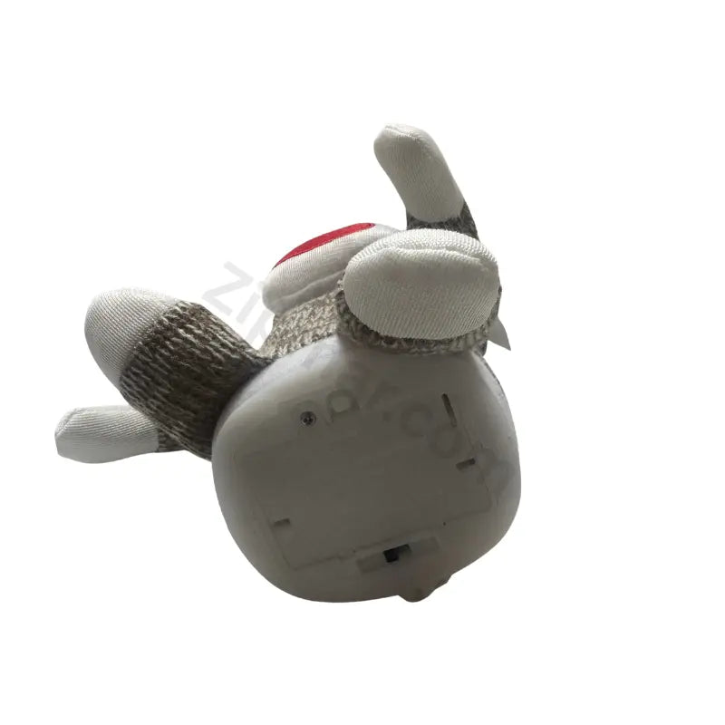 Sock monkey plush toy underside showing the battery compartment cover and white fabric feet