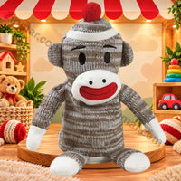 Thumbnail for Sock monkey plush toy in brown and gray knit with a red pom pom hat, white face and red smile standing on a wooden stand