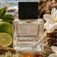 Thumbnail for Curations By The Good Scent Coastal Musk eau de parfum 3.4 fl oz clear square glass bottle with black wood grain cap on a beach with limes and white flowers