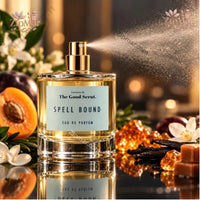 Thumbnail for The Good Scent Spell Bound Eau de Parfum 3.4 oz clear glass bottle actively spraying with apricot and white flower styling