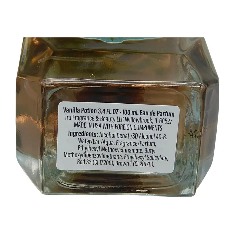 Close-up of the white circular sticker on the bottom of the Tru Fragrance Vanilla Potion EDP bottle, showing ingredients and "Made in USA" information.