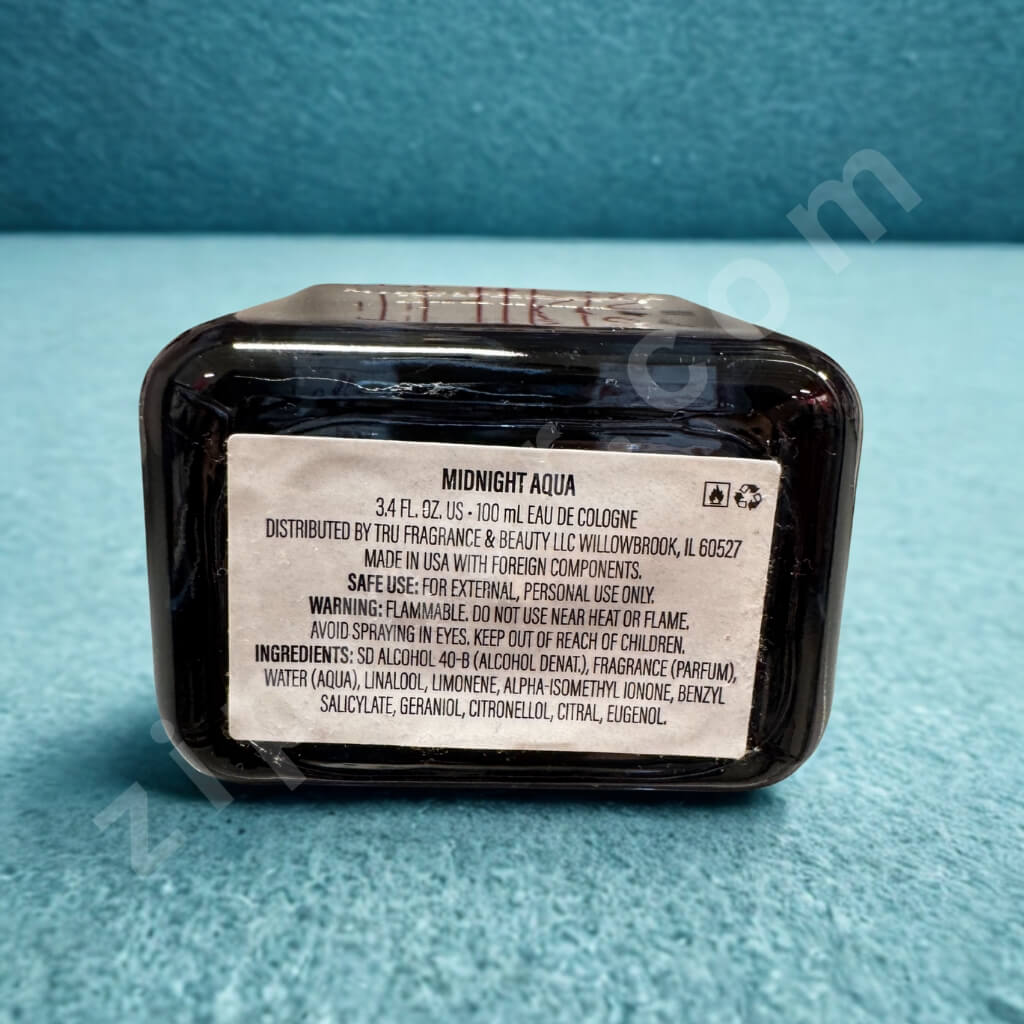 Back of a black cologne bottle labeled 'Midnight Aqua' on a blue background