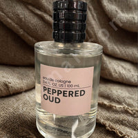 Thumbnail for Perfume bottle labeled 'Peppered Oud' on a textured fabric background