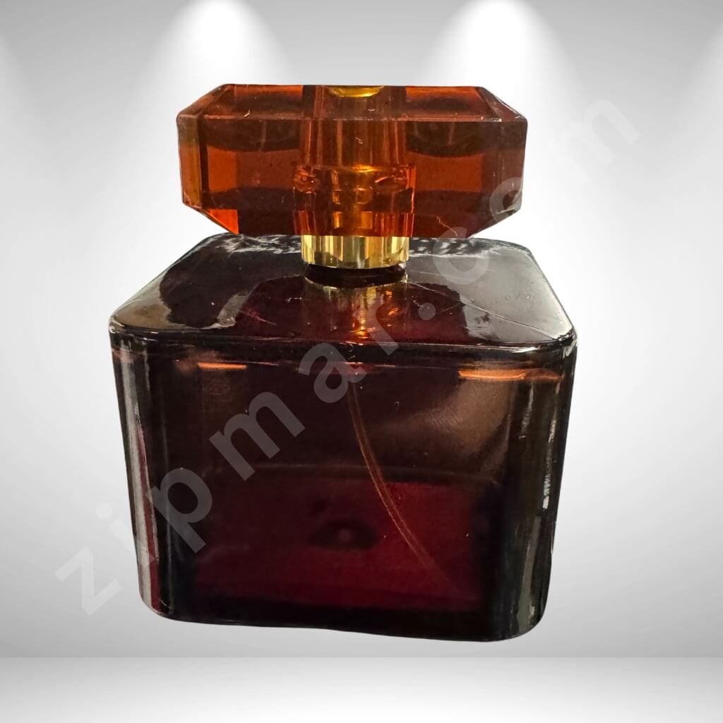 Amber glass perfume bottle with a gold cap on a light gray background