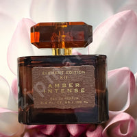 Thumbnail for Amber Intense perfume bottle with pink flowers in the background