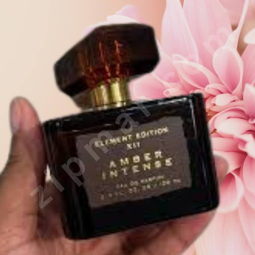 Perfume bottle labeled 'Amber Intense' held in front of pink flowers